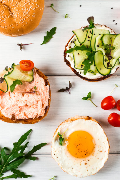 三明治、白面包、煎蛋、奶油芝士、黄瓜、毛鱼子酱、芝麻小面包，各种各样的早餐，放在白色的桌子上，竖着，没有人，图片下载