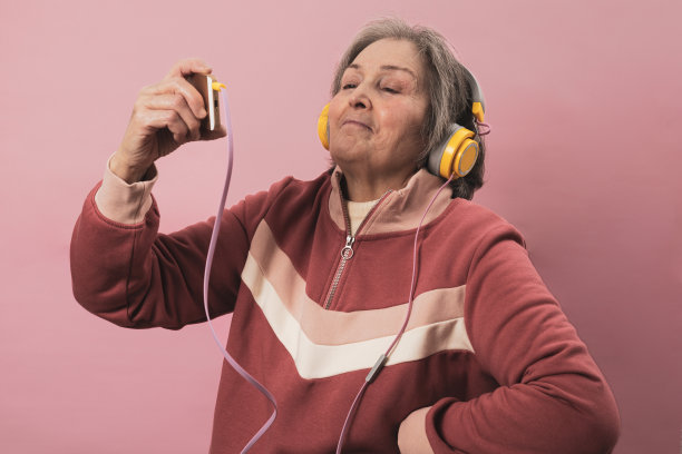 一位身穿运动服的70岁老太太在粉色背景下摆拍。图片下载