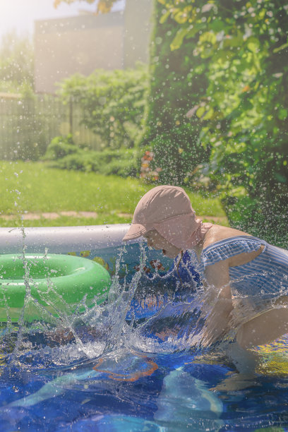 一个阳光明媚的日子，小女孩在水池里戏水图片下载