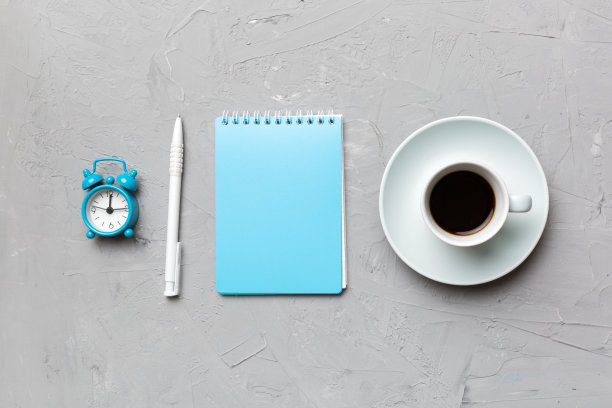 现代办公桌上配有笔记本电脑和咖啡杯等用品。空白的笔记本页面为您设计。俯视图，平铺图片下载