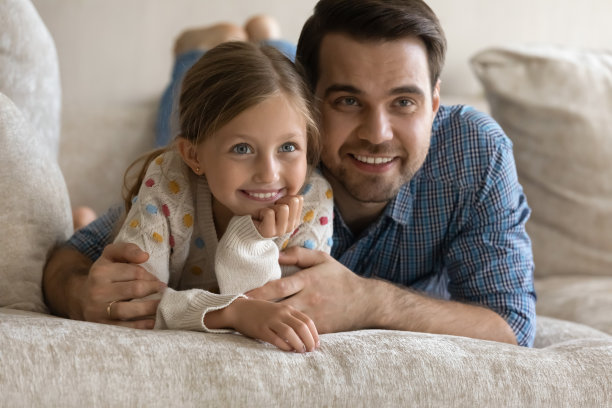 年轻的父亲和孩子一起看电视。图片下载