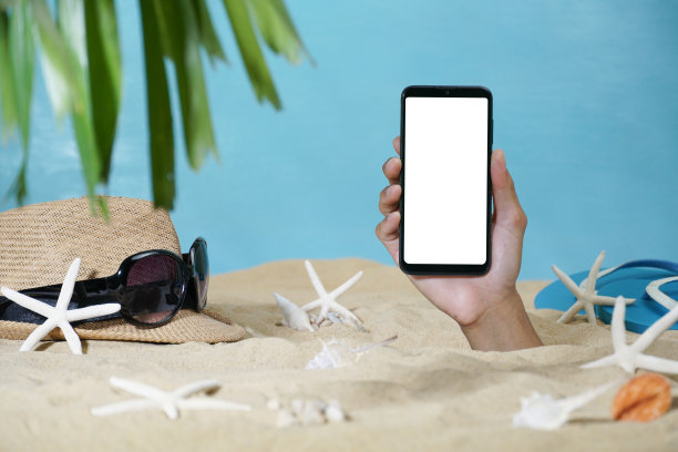 手拿着白色的智能手机穿过沙滩。在智能手机上创建媒体。图片下载