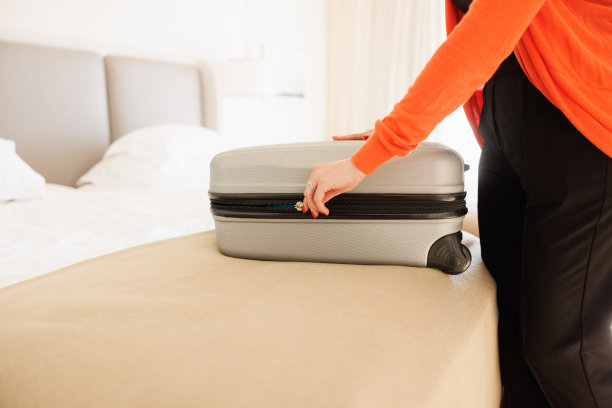 在酒店房间的床上打开小行李箱的女人的腹部图片下载