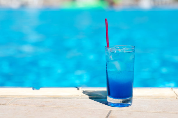 游泳池附近有冰的蓝色泻湖鸡尾酒。夏季饮料。图片下载
