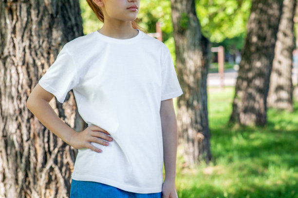 一个十几岁的女孩穿着白色t恤在城市公园散步的特写。图片下载