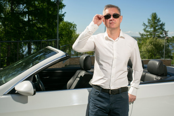 在敞篷车附近有个戴墨镜的帅哥。奢侈的生活图片下载