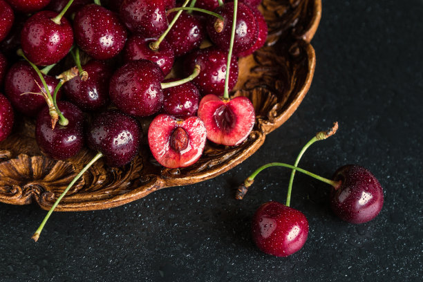 新鲜的红樱桃被放在一个有水滴的木盘子上图片下载