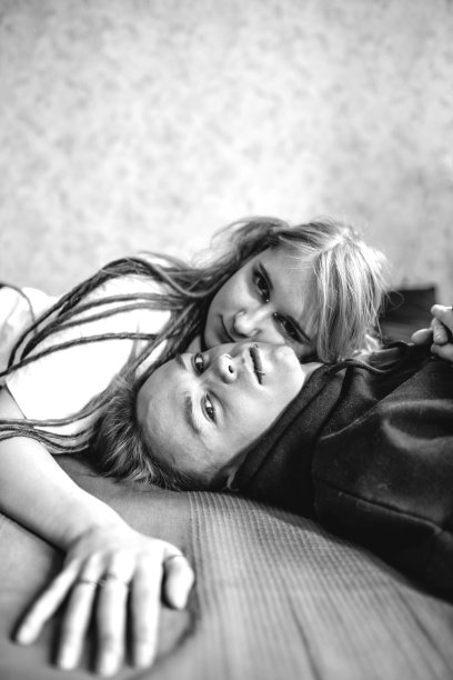 一个年轻的纹身朋克夫妇的肖像，一个女孩和一个染了色的长发编成辫子的男孩，躺在一张大床上。时尚现代的青年。图片下载