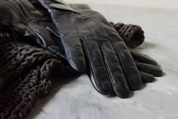 针织围巾上戴着女性黑色皮手套图片下载