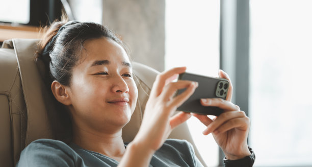 一个年轻聪明的亚洲女性手持和使用智能手机的特写图像。呆在家里。图片下载