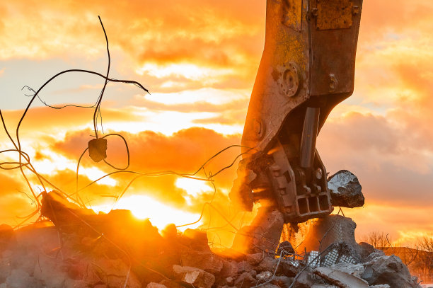 强大的破碎机摧毁装甲水泥剩余物在日落图片下载