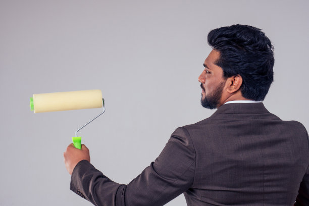 在工作室拷贝空间的白色背景上，年轻的商人手里拿着画笔图片下载