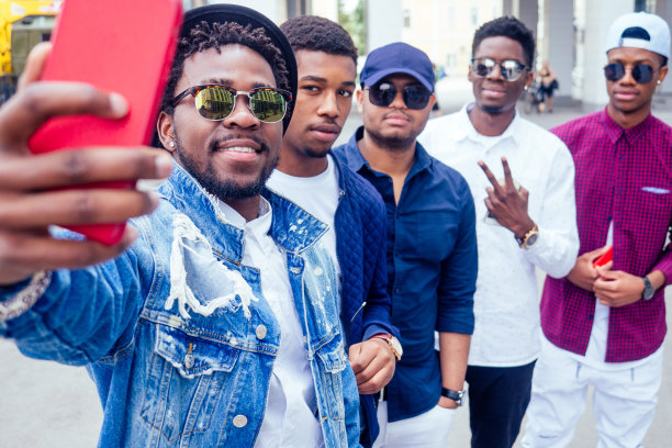 一组5个时尚酷的非洲裔美国人学生在街上交流，看智能手机在街上拍照片自拍图片下载