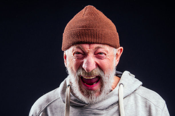 肖像悲伤老人男流浪汉戴着温暖的棕色帽子和漏手套，拿着金属罐装银行罐的钱在工作室的黑色背景图片下载