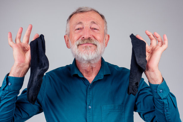 头和肩膀肖像的中年男子持有好臭干净的袜子织物柔顺剂在工作室的白色背景图片下载