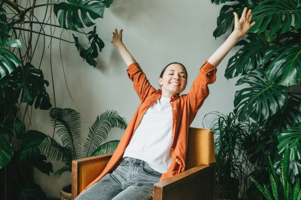 一个悠闲的年轻女子坐在房子美丽的花园里放松。一位女花匠，园丁正在休息后照顾家庭花园的室内植物。健康，休息和工作与生活的平衡图片下载