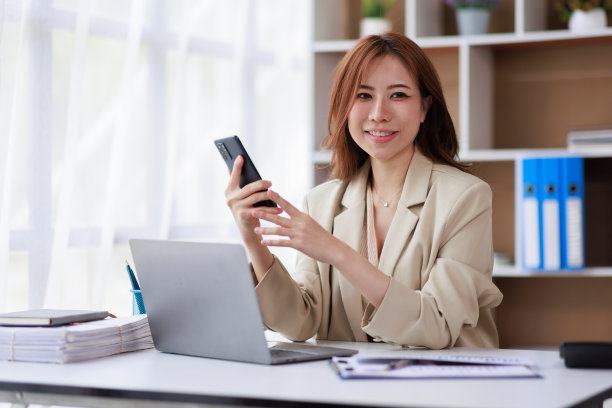 亚洲女商人在现代家庭办公室使用手机和笔记本电脑工作。图片下载