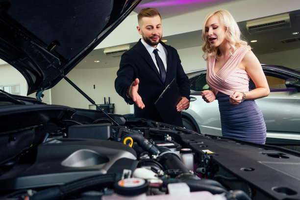 在经销商沙龙，穿着西装的白人推销员向漂亮的金发女顾客展示商品目录图片下载