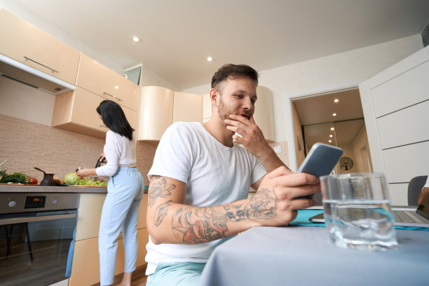 妻子在厨房做饭时，男人在刷手机图片下载