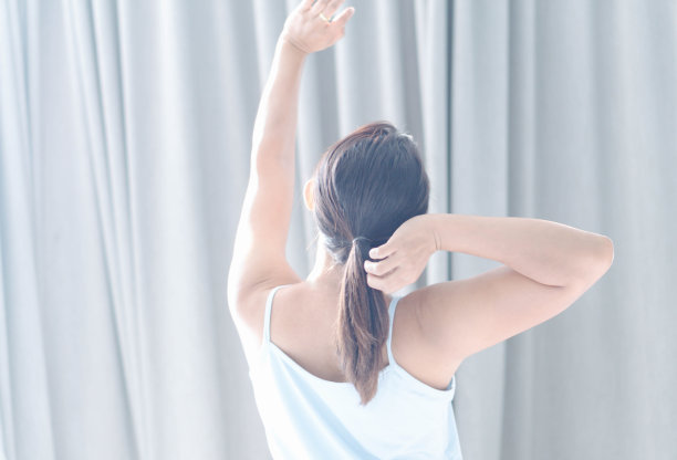 近距离的女人坐在床上和伸展后，早上醒来放松与灯光背景图片下载