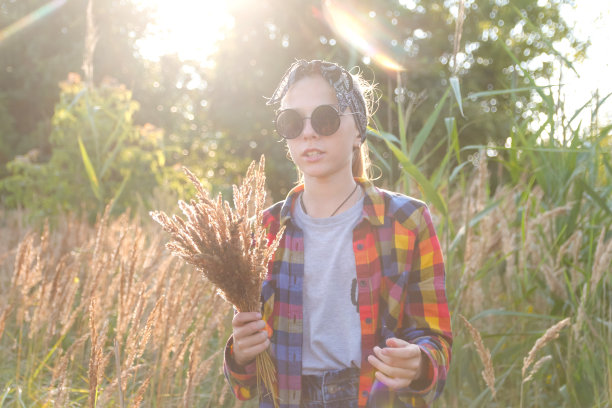 分散的青少年或十几岁的女孩走在自然背景。小女孩拿着一束潘帕斯草原。绿色的草地,字段。潮人。肖像太阳镜。的梦想。秋天。的生活方式。的焦点图片下载
