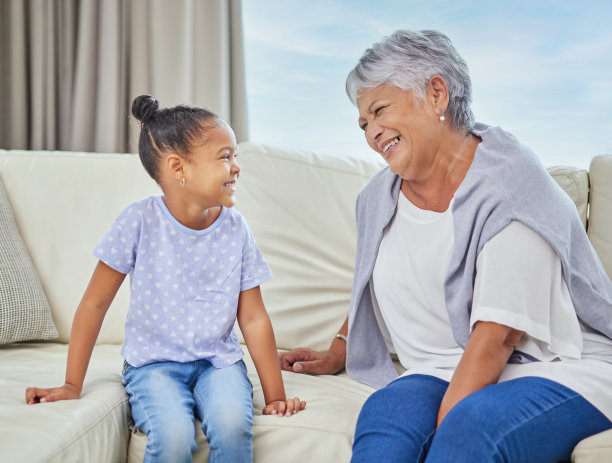 微笑可爱的混血小女孩拥抱她的祖母，在家里与她建立联系。美丽的西班牙成熟的女人显示爱和感情孙女在客厅图片下载