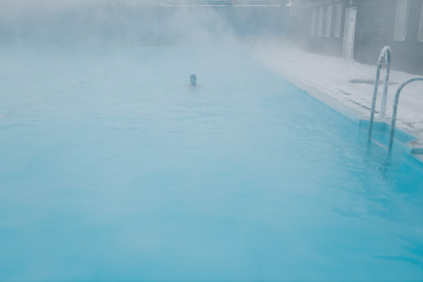 健美游泳运动员男性训练游泳在开放的冬季游泳池与雾。地热户外水疗概念，图片下载
