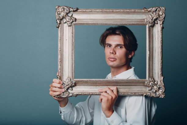 肖像年轻人站在画室与相框。图片下载