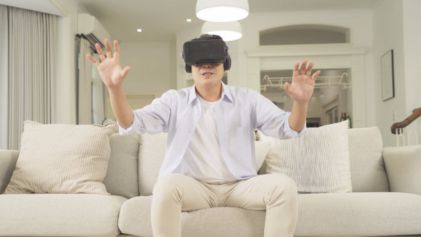 一名亚洲商务青年，戴着VR或虚拟现实眼镜，戴着元宇宙头戴设备，坐在会议室里在线玩电子游戏。的乐趣。图片下载