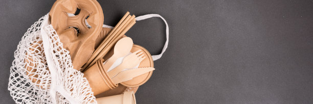 生态纸餐具套装，生态餐具-纸杯，容器，木制竹制餐具和饮用吸管在网棉袋在深灰色的混凝土背景，文本拷贝空间。可持续食品包装理念的旗帜图片下载