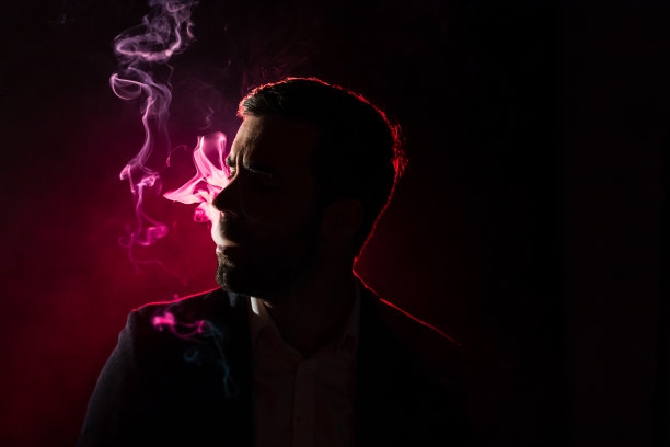 一名男子在黑暗中吸烟的照片。图片下载