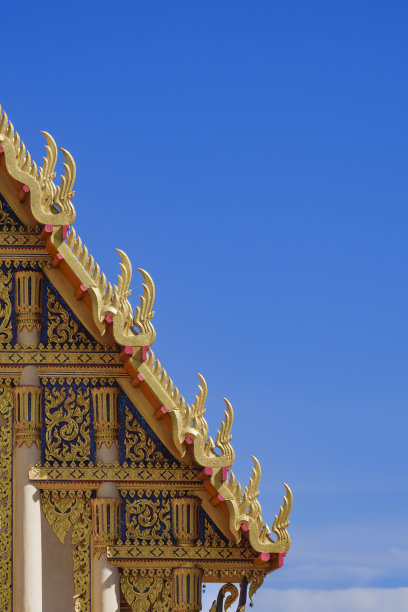 美丽的金色山墙顶在传统泰国寺庙的屋顶上，以蓝天为背景图片下载