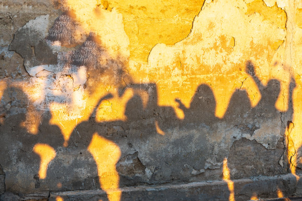 日落时分，老石墙上跳舞的人的影子。图片下载