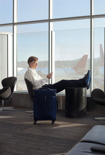 商人在机场候机楼边玩手机边休息图片下载