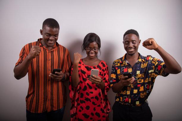 两个男孩和一个女孩看着他们的智能手机屏幕很高兴，在工作室的广告照片，幸福和胜利的概念图片下载