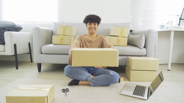 一个亚洲快乐女人女孩在家网上工作，销售产品，包装邮政包裹包装纸箱快递，在社交媒体。网上购物的业务。中小企业电子商务。人们的生活方式。图片下载