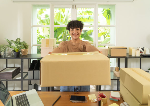 一个亚洲快乐女人女孩在家网上工作，销售产品，包装邮政包裹包装纸箱快递，在社交媒体。网上购物的业务。中小企业电子商务。人们的生活方式。图片下载