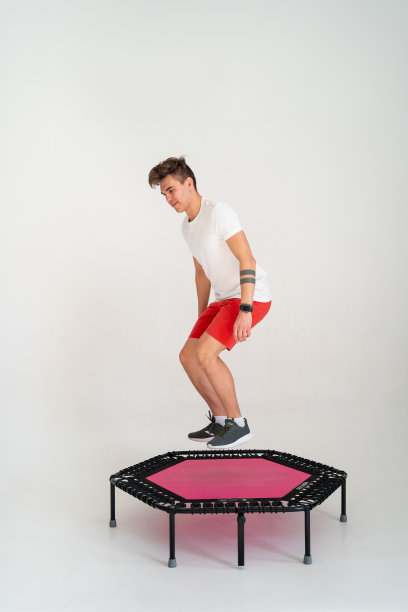 强壮的健身男子穿着运动服在蹦床上跳跃图片下载