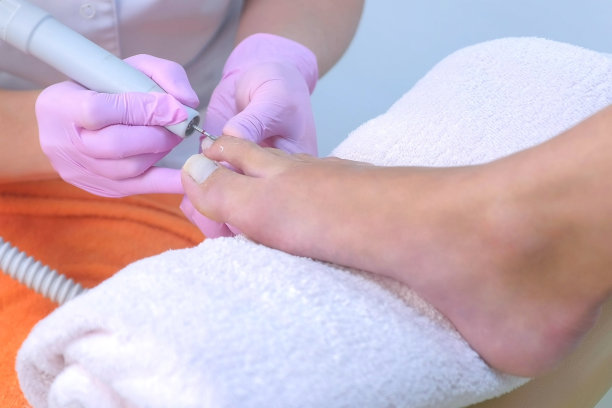 女足疗师使用电动指甲机去除客户脚趾角质层。图片下载