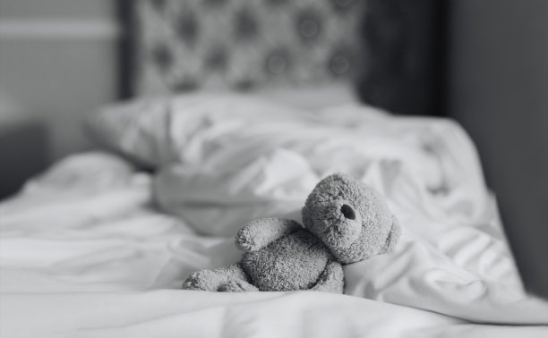 泰迪熊躺在卧室的床上，阳光从窗户照进来，黑白照片孤独的棕熊独自呆在家里，孤独的概念，国际失踪儿童日图片下载