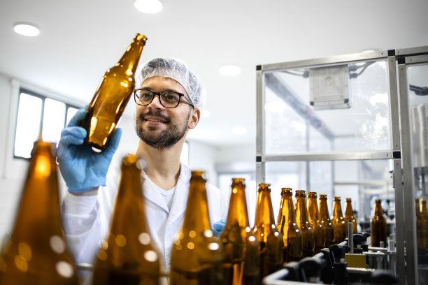 工厂技术人员检查啤酒饮料厂玻璃瓶的纯度和清洁度。图片下载