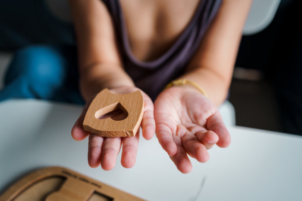 一个孩子拿着一个心形的木制拼图。图片下载