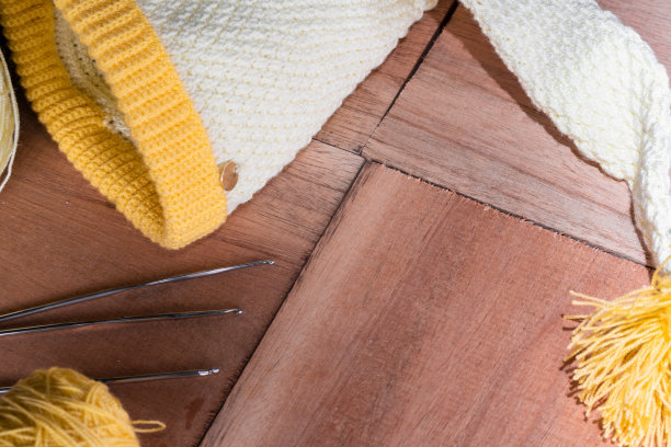 为宝宝钩针编织小精灵帽，放在木板上，旁边放两卷黄白纱，材料开始钩针编织。在家工作的概念。准备迎接冬天的到来。图片下载