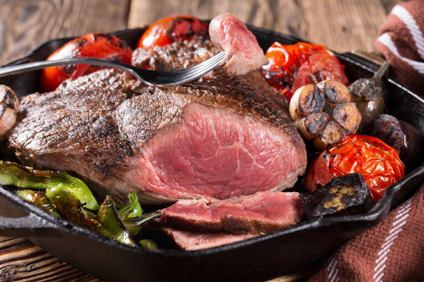 肉:在铸铁锅中与蔬菜一起烤的一块肉图片下载
