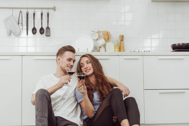 幸福的情侣喜欢一边在厨房做饭，一边喝咖啡。年轻相爱的男女在厨房里一起喝咖啡或茶。图片下载