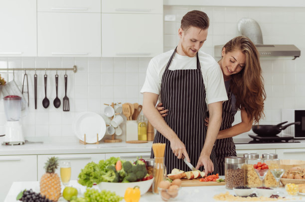 幸福的夫妻喜欢一起在厨房做饭。年轻的爱的男人和女人笑着在家里做健康的食物。图片下载
