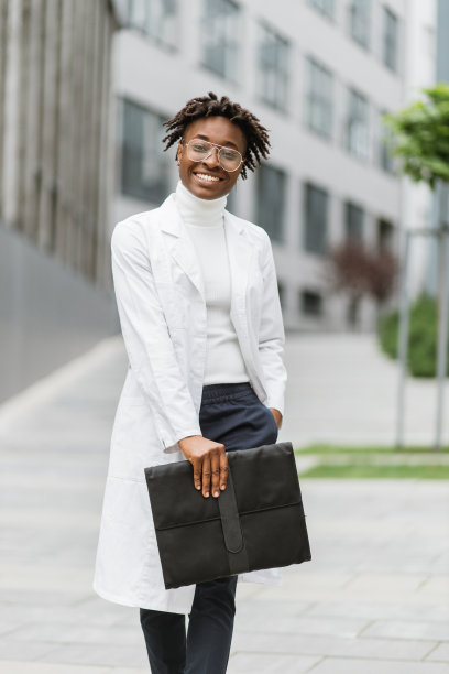 身穿白大褂的非裔美国女医生或女学生，站在现代诊所外图片下载