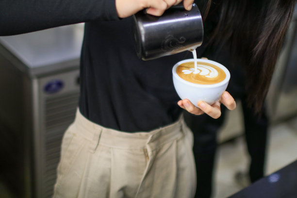 咖啡拿铁艺术，由咖啡师将蒸牛奶倒入咖啡杯在咖啡馆。图片下载