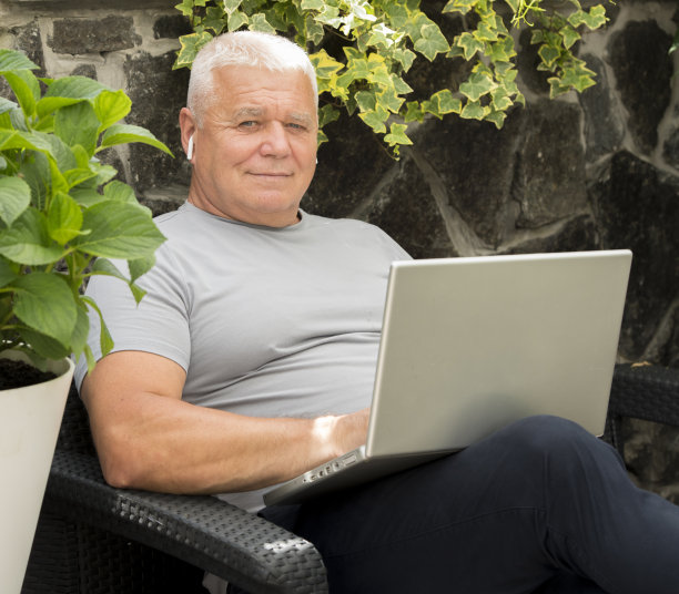 一位老人在花园里用笔记本电脑图片下载