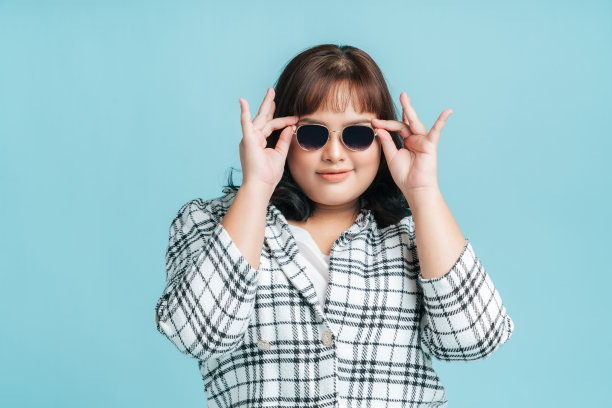 肖像美丽自信的亚洲女性加尺寸模型戴墨镜在孤立的浅蓝色工作室背景。图片下载